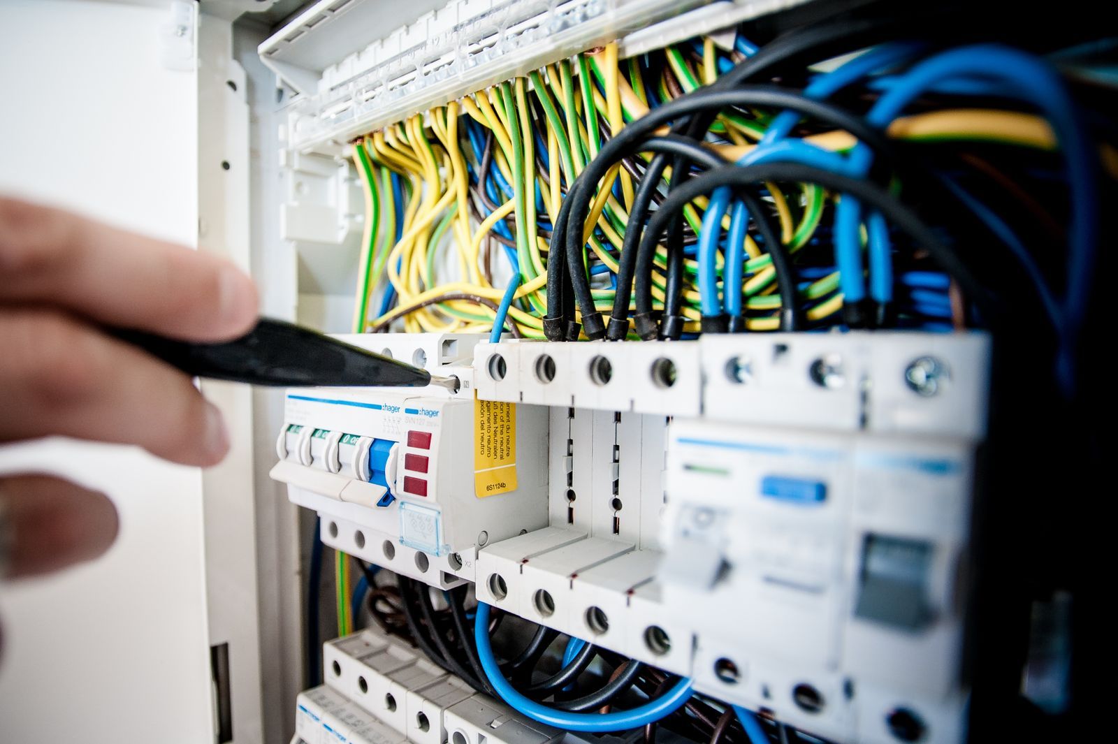 An electrician working on an open switchboard, illustrating tradie service work