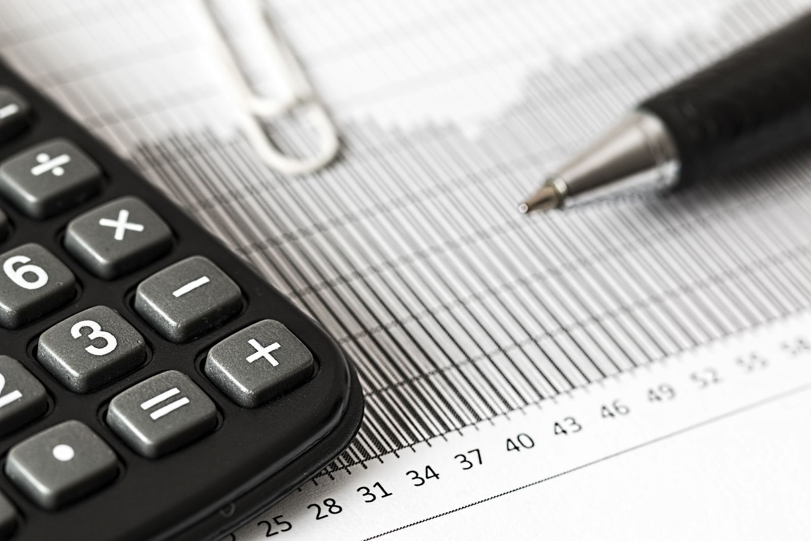 A calculator and pen beside a financial chart, illustrating website package costs